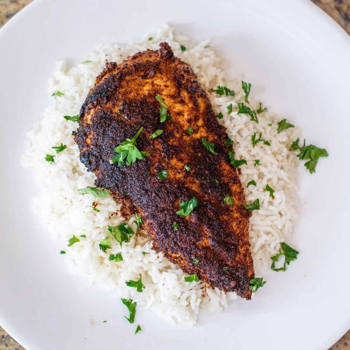 Sliced Cajun Blackened Chicken served over steaming rice, garnished with parsley and ready for dinner.  