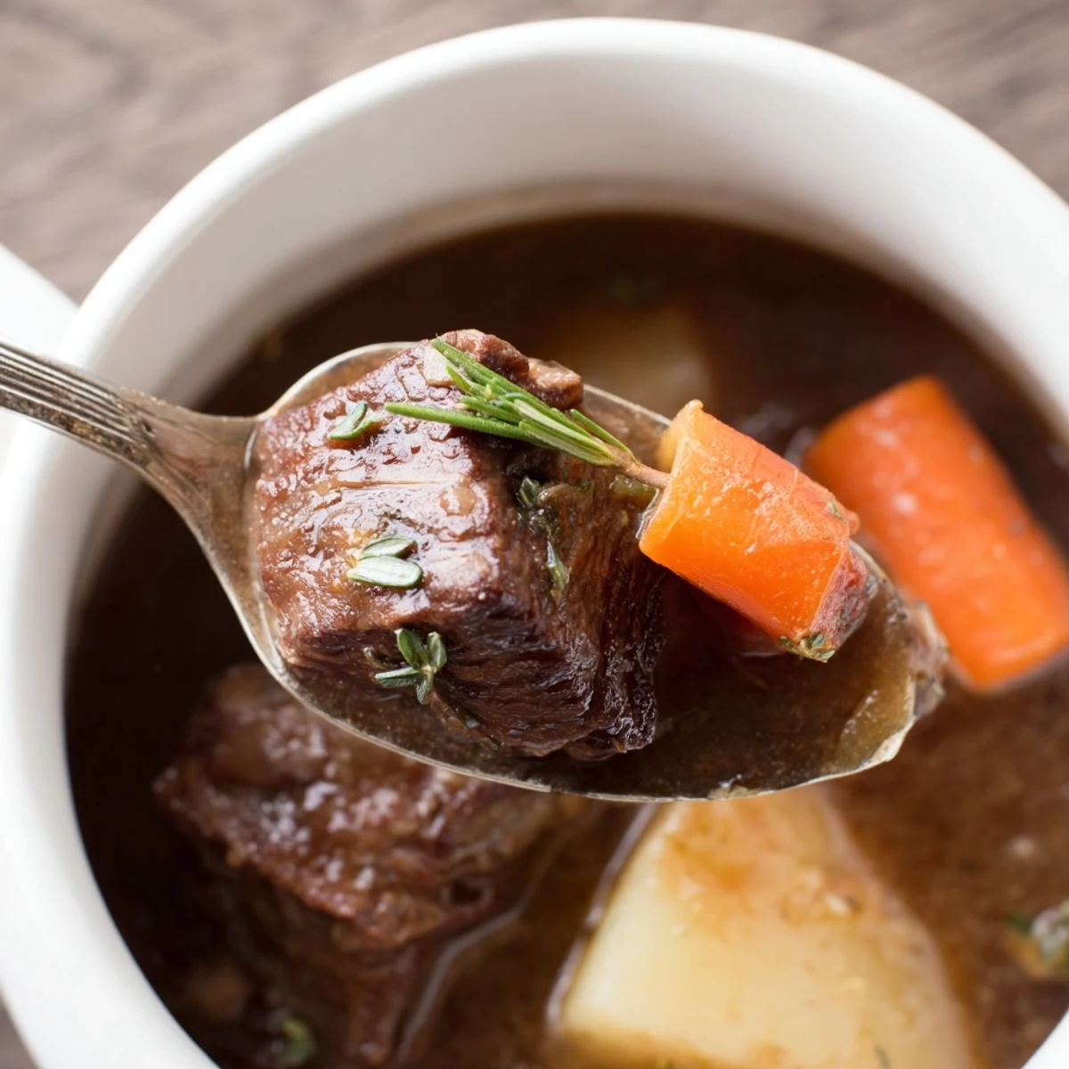 Slow cooker beef stew with carrots and potatoes steaming in a rustic ceramic bowl, garnished with fresh parsley.