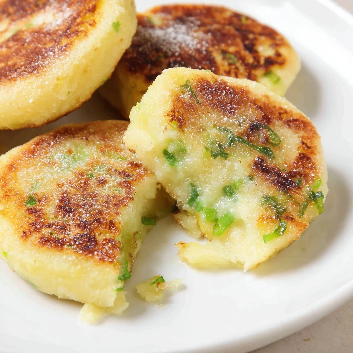 Pan-fried Irish Potato Cakes with Scallions sizzling golden brown in a skillet.