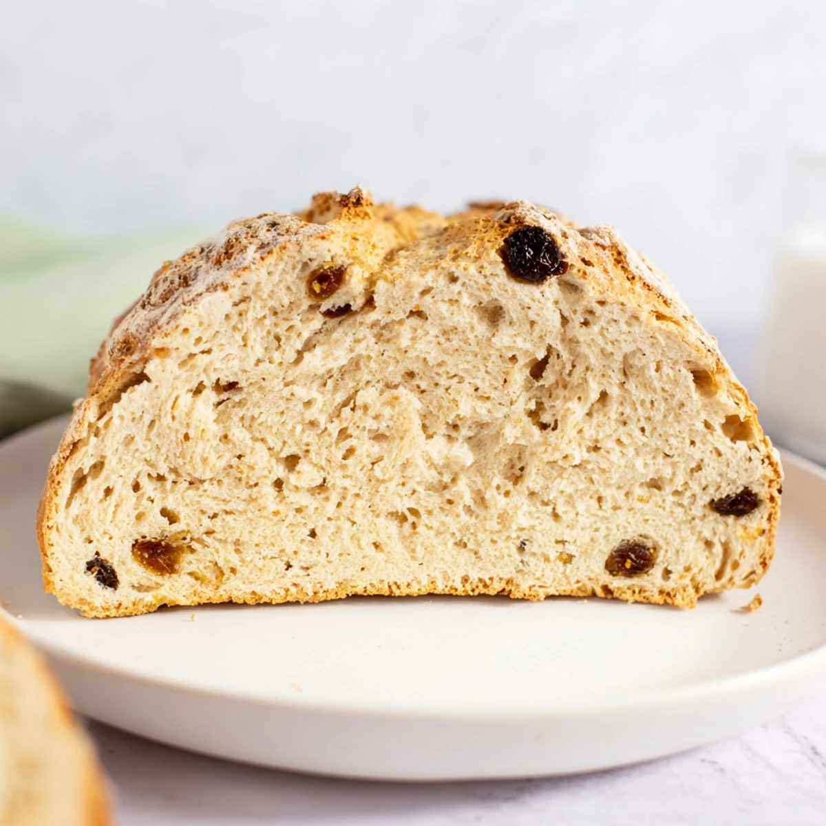 Warm Irish Soda Bread with Currants and Caraway sits on a cooling rack, ready for breakfast with butter.