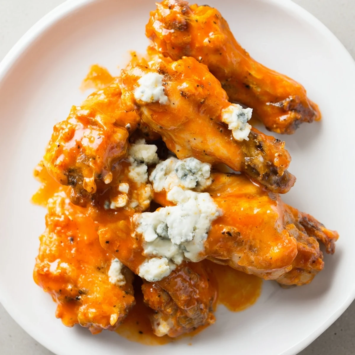 Hearty platter of Crispy Buffalo Chicken Wings with Blue Cheese Dip, drizzled with sauce and paired with crunchy veggies.