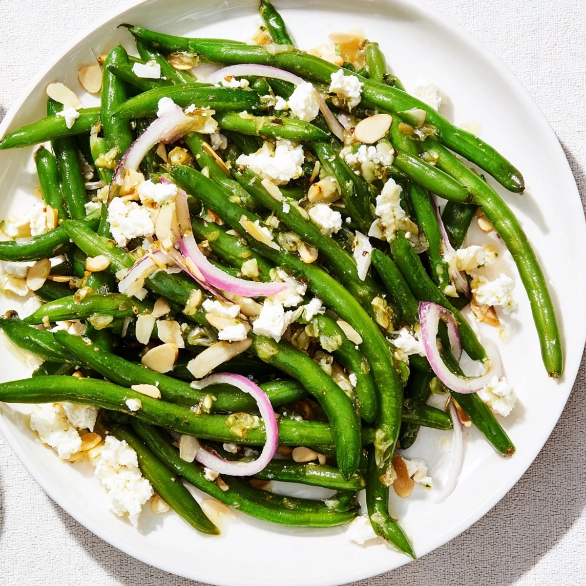 Vibrant green beans tossed in zesty lemon dressing, topped with creamy feta and crunchy toasted almonds in this refreshing Green Bean Salad with Feta and Almonds.