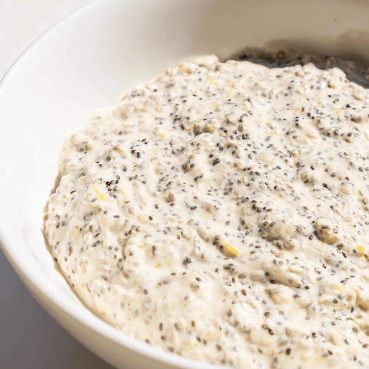 This overnight oats recipe shows a spoon scooping the chilled, tangy lemon breakfast from a glass jar.