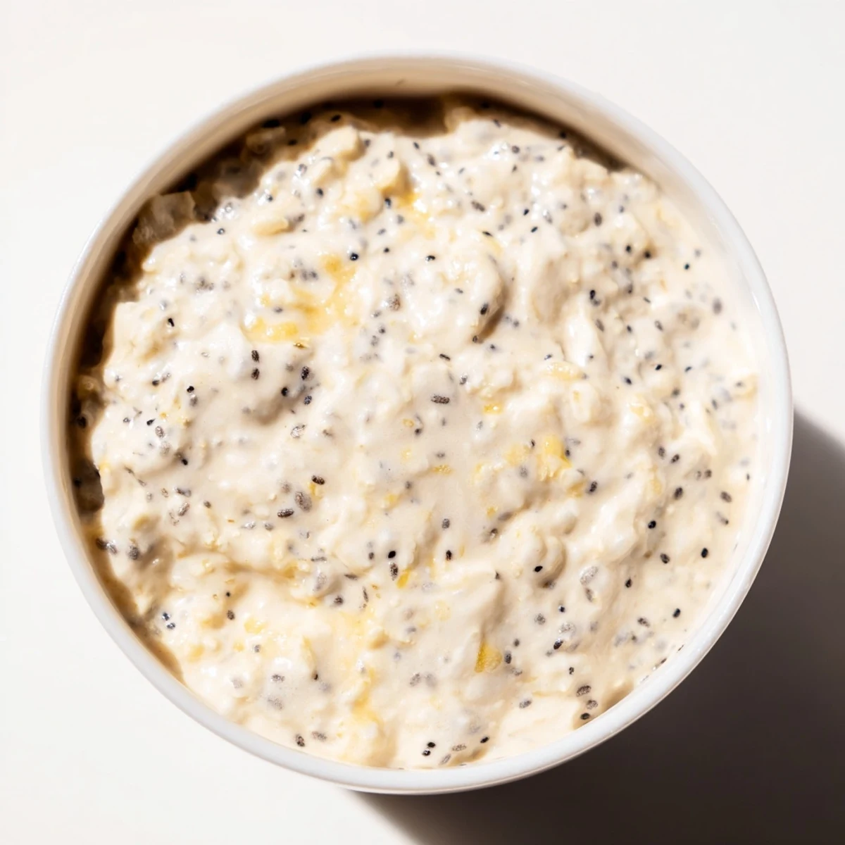 Creamy vegan lemon poppy seed overnight oats in a jar topped with fresh berries and sliced almonds.