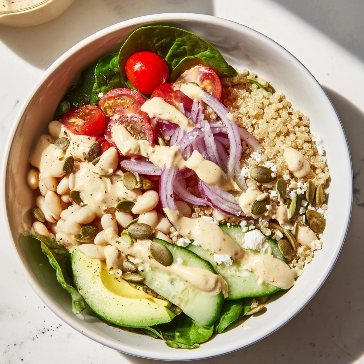 In this close-up of Spinach & White Bean Ultimate Protein Power Bowl, fresh spinach and diced cucumber add crisp texture beside fluffy quinoa and white beans.
