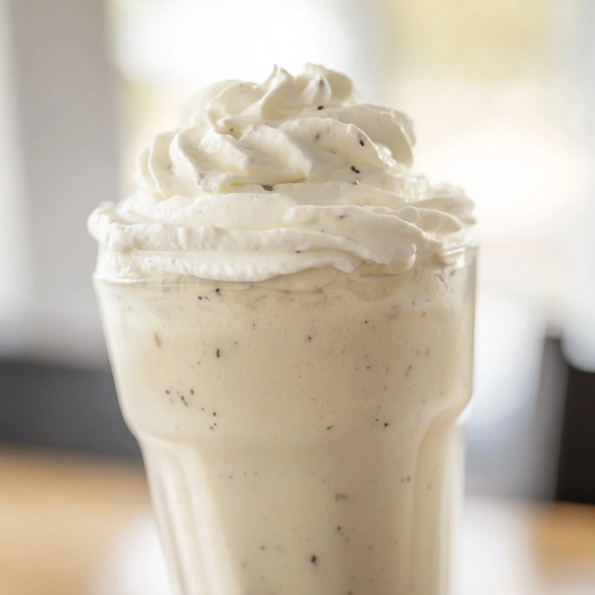 Cold Vanilla Bean Frappuccino in a frosty glass, garnished with whipped cream for a delicious coffeehouse vibe.