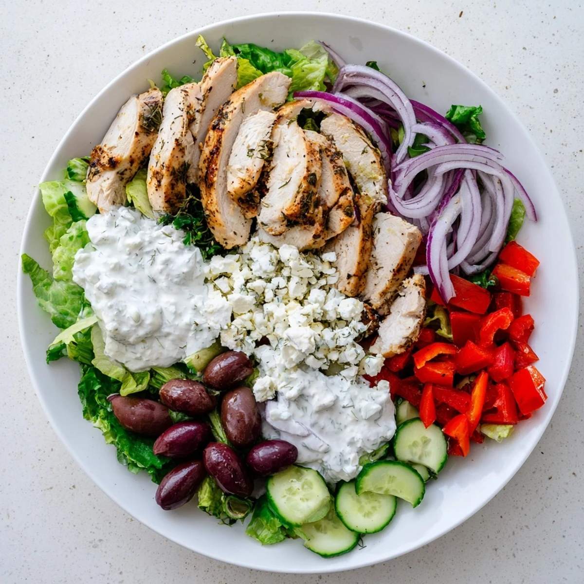 Freshly grilled chicken slices rest on a bed of greens, topped with creamy Tzatziki Chicken Salad featuring cucumber and dill.