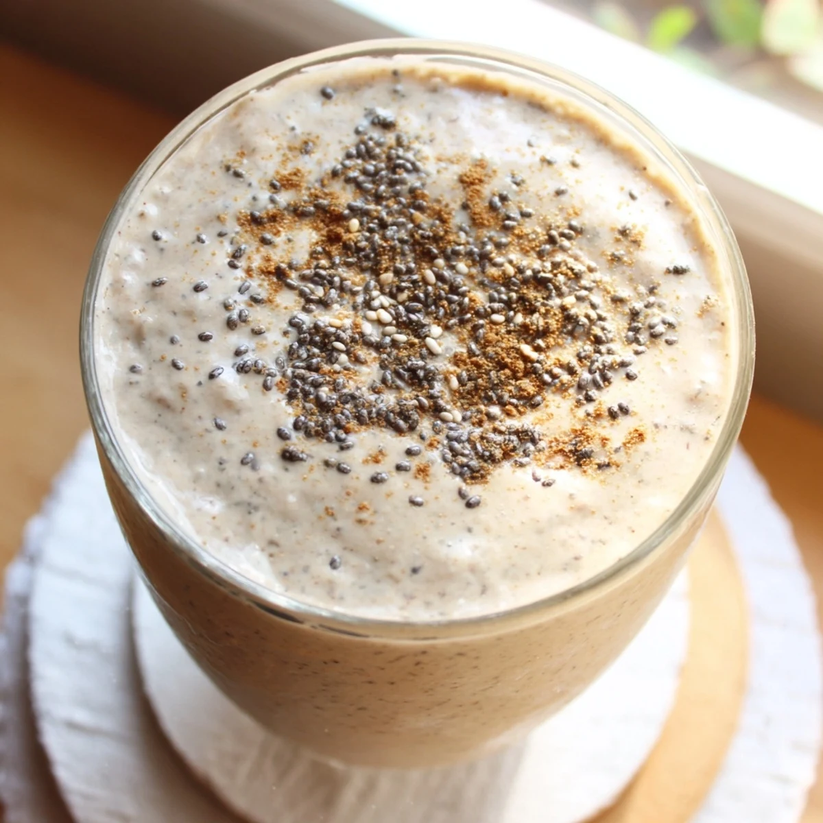 Protein-packed Greek yogurt banana smoothie in clear glasses showing the smooth beige texture and bubbles
