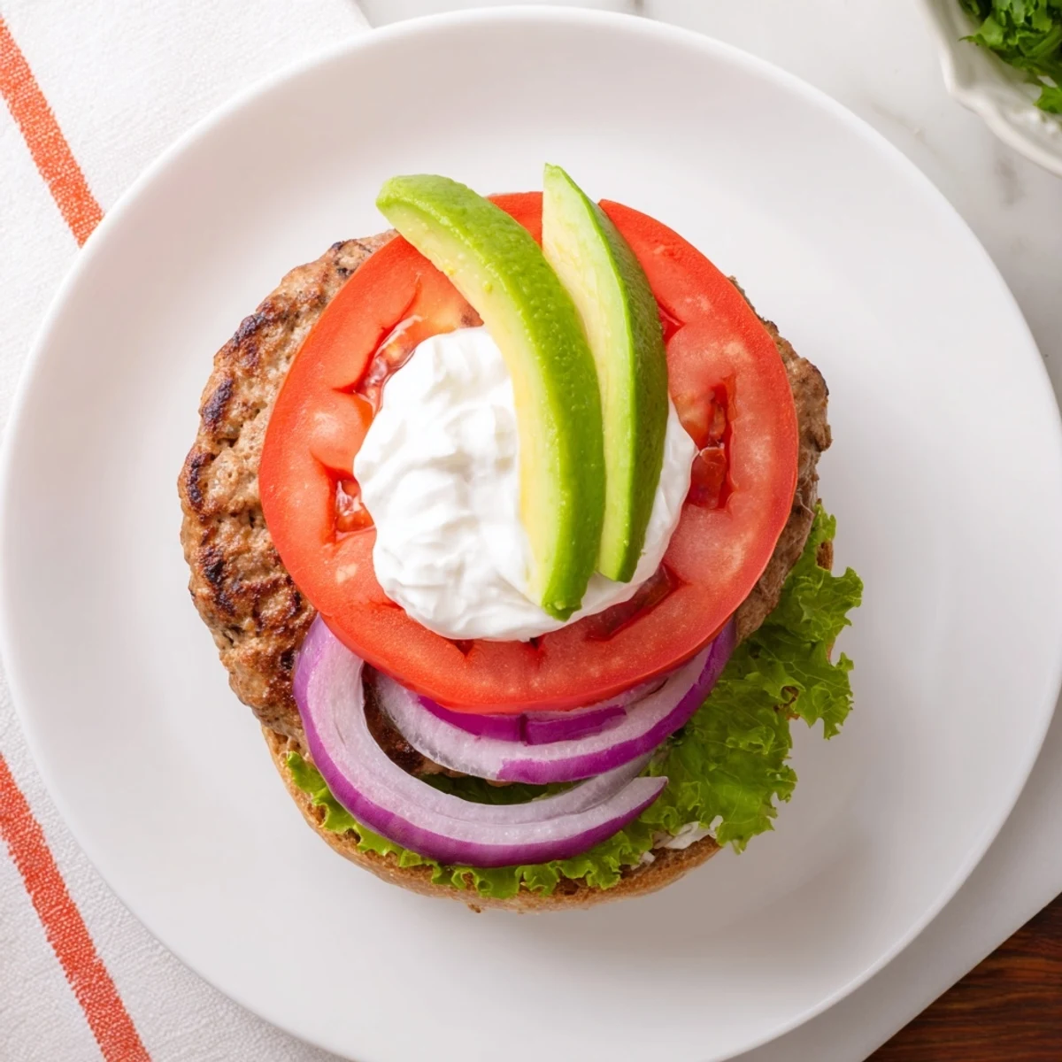 Golden brown healthy high protein burger patty stacked with fresh toppings and Greek yogurt sauce