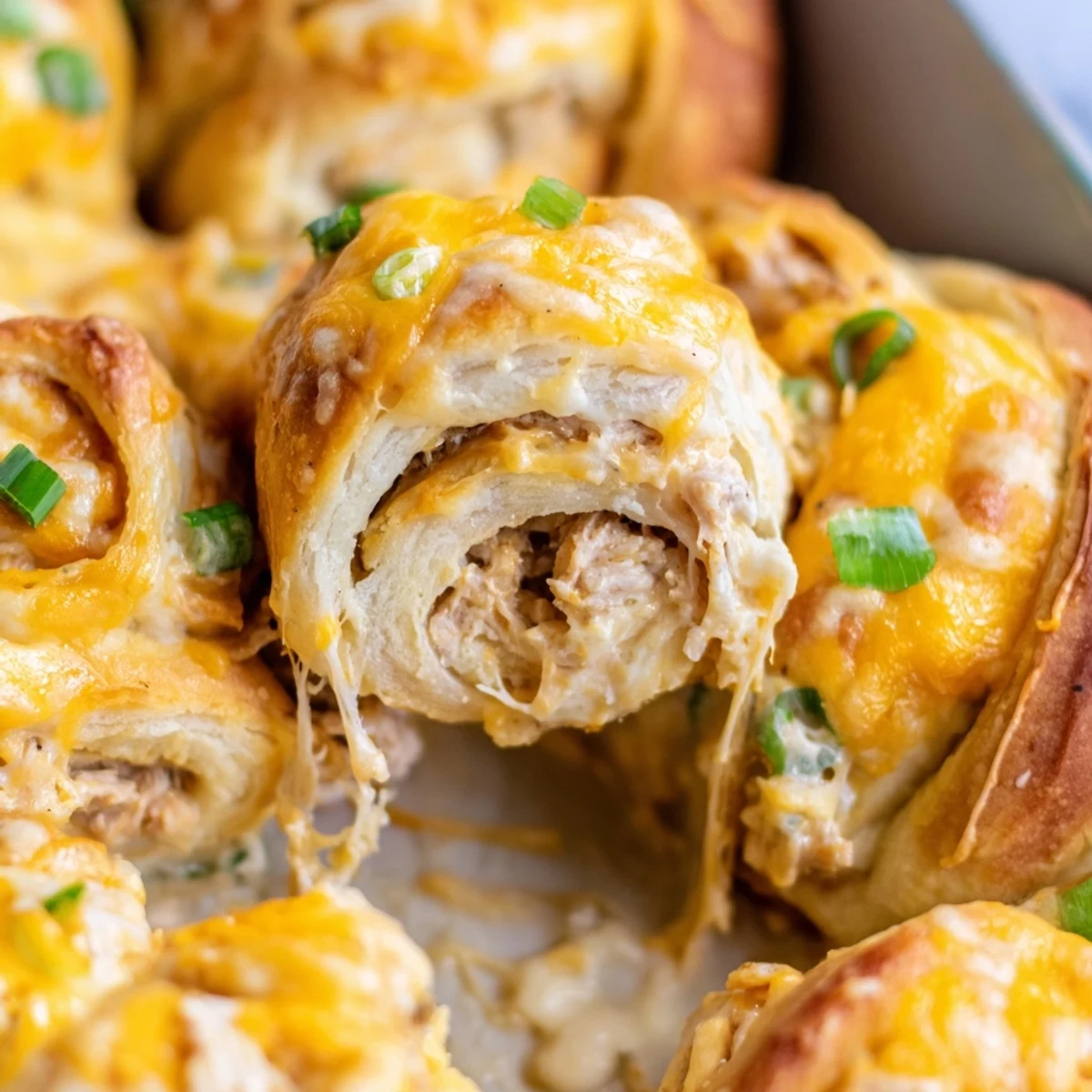 Golden brown cheesy chicken crescent bake with bubbling mozzarella topping on a white plate