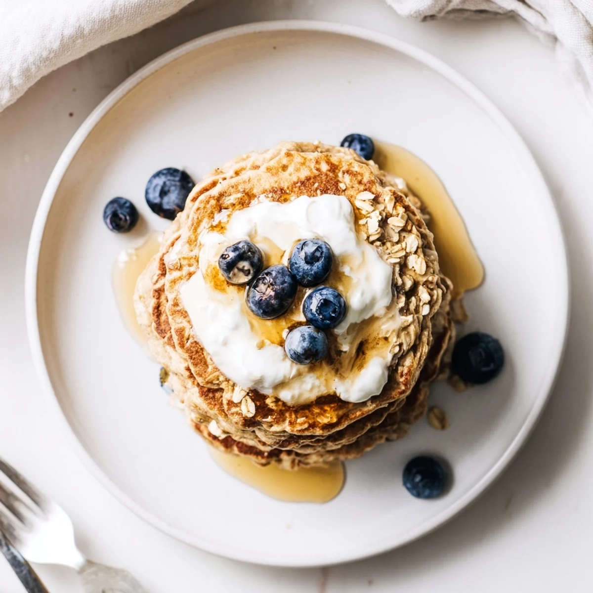 Homemade banana oatmeal pancakes served with fresh berries and a generous dollop of Greek yogurt