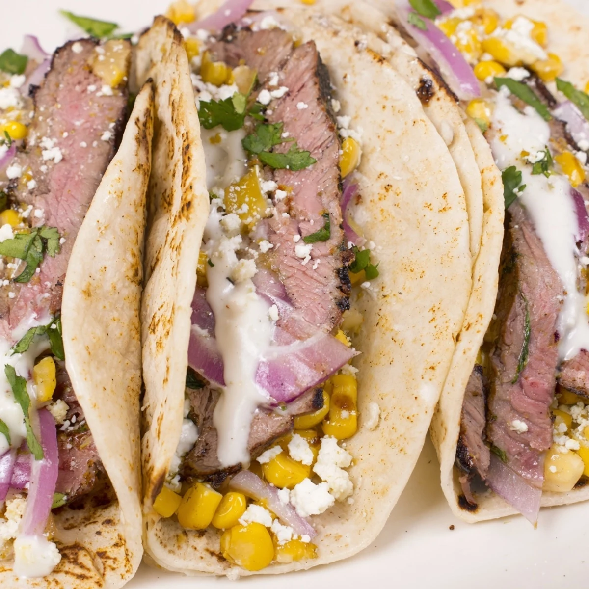 Delicious grilled steak elote tacos featuring spicy marinated meat and creamy Mexican street corn topping