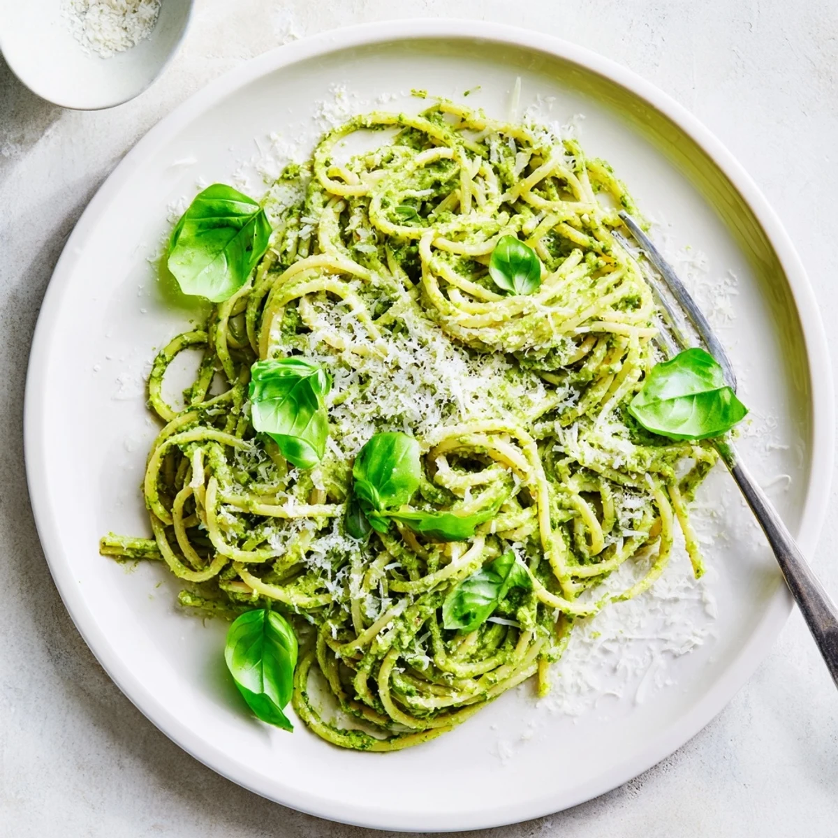 Close-up of spaghetti noodles smothered in bright green avocado spinach and basil pesto sauce