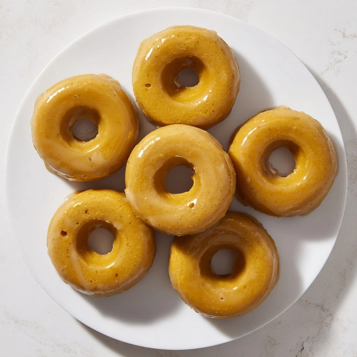 Golden maple pumpkin mochi donuts with sweet glaze drizzled over chewy pumpkin-spiced rings