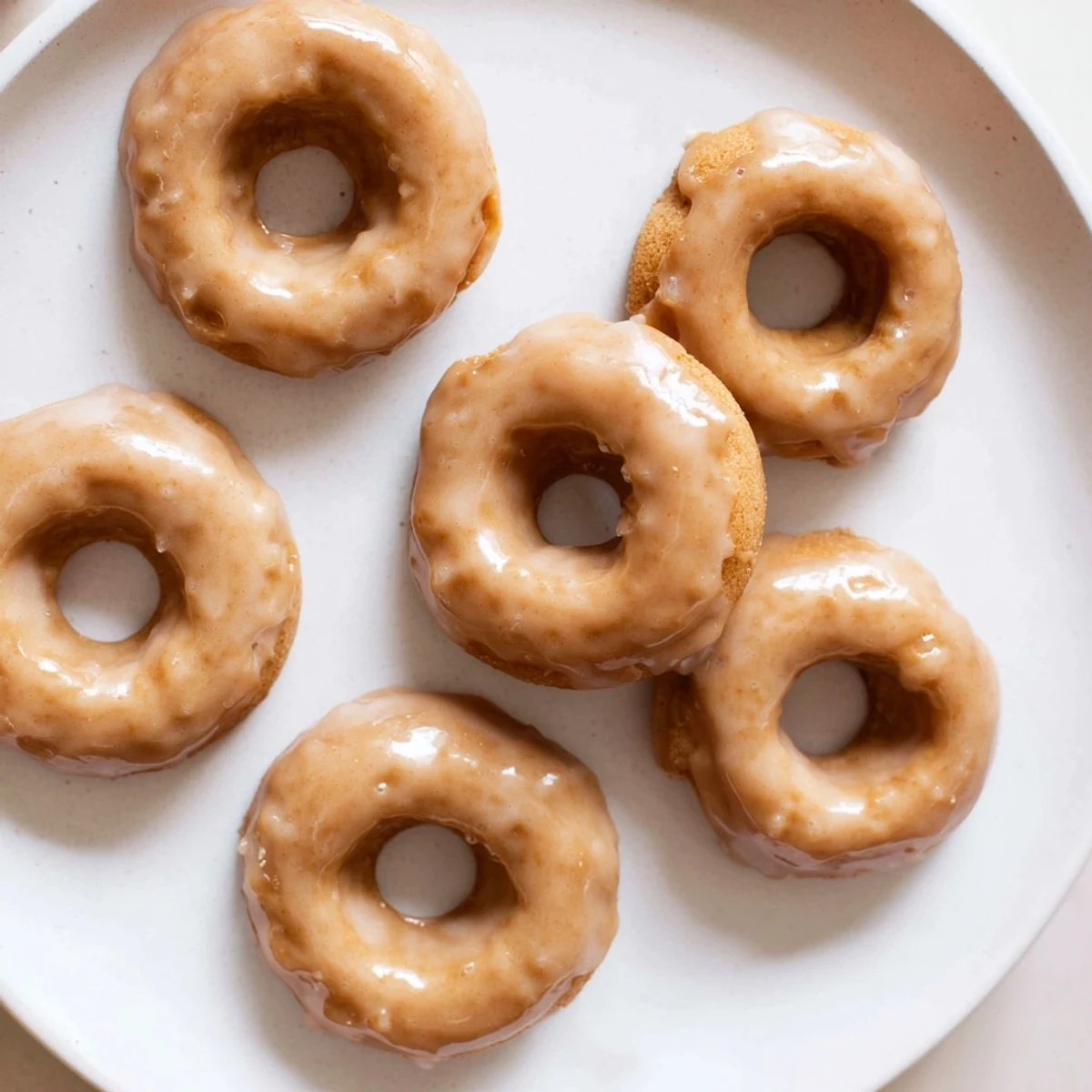 Baked pumpkin mochi donuts topped with glossy maple glaze on a wire cooling rack