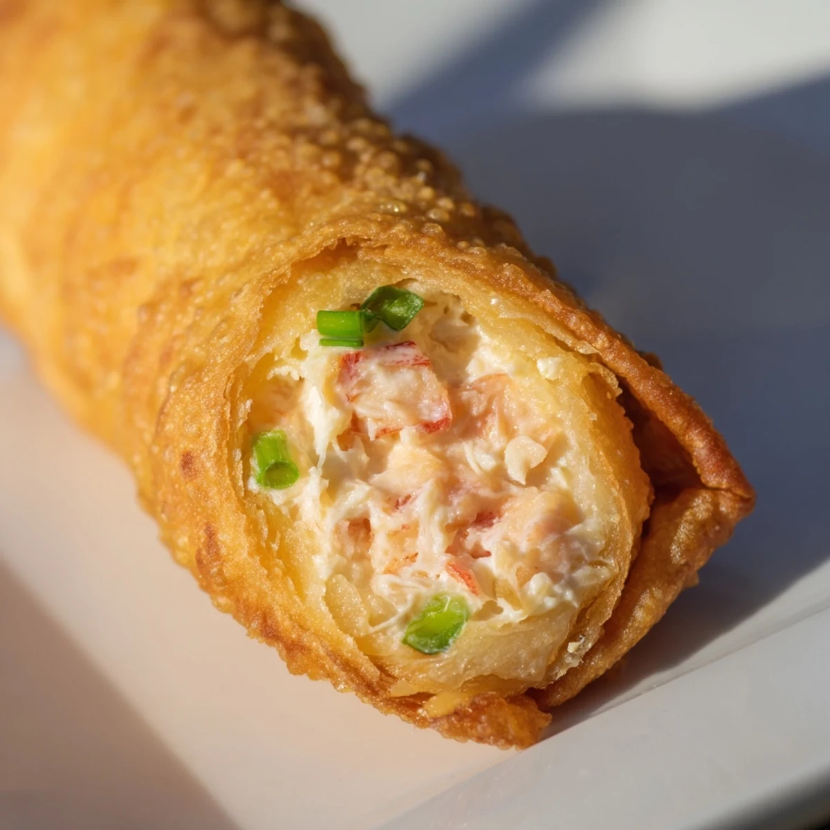 Homemade Crab Rangoon egg rolls plated with sweet chili dipping sauce for parties