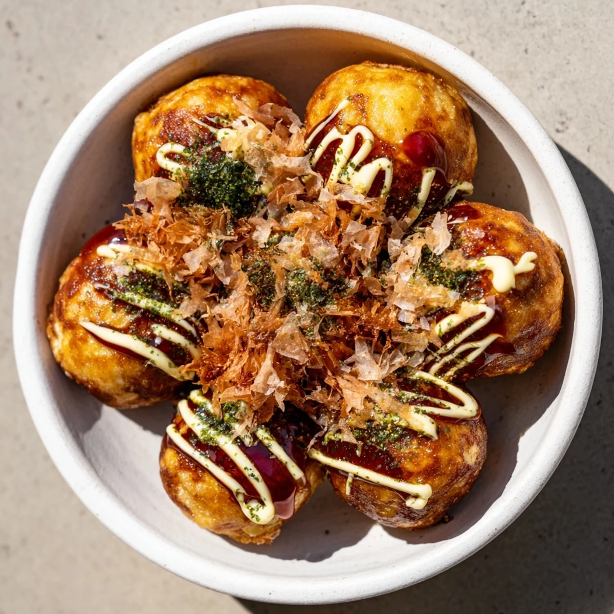 Golden brown Takoyaki balls drizzled with savory sauce and topped with dancing bonito flakes