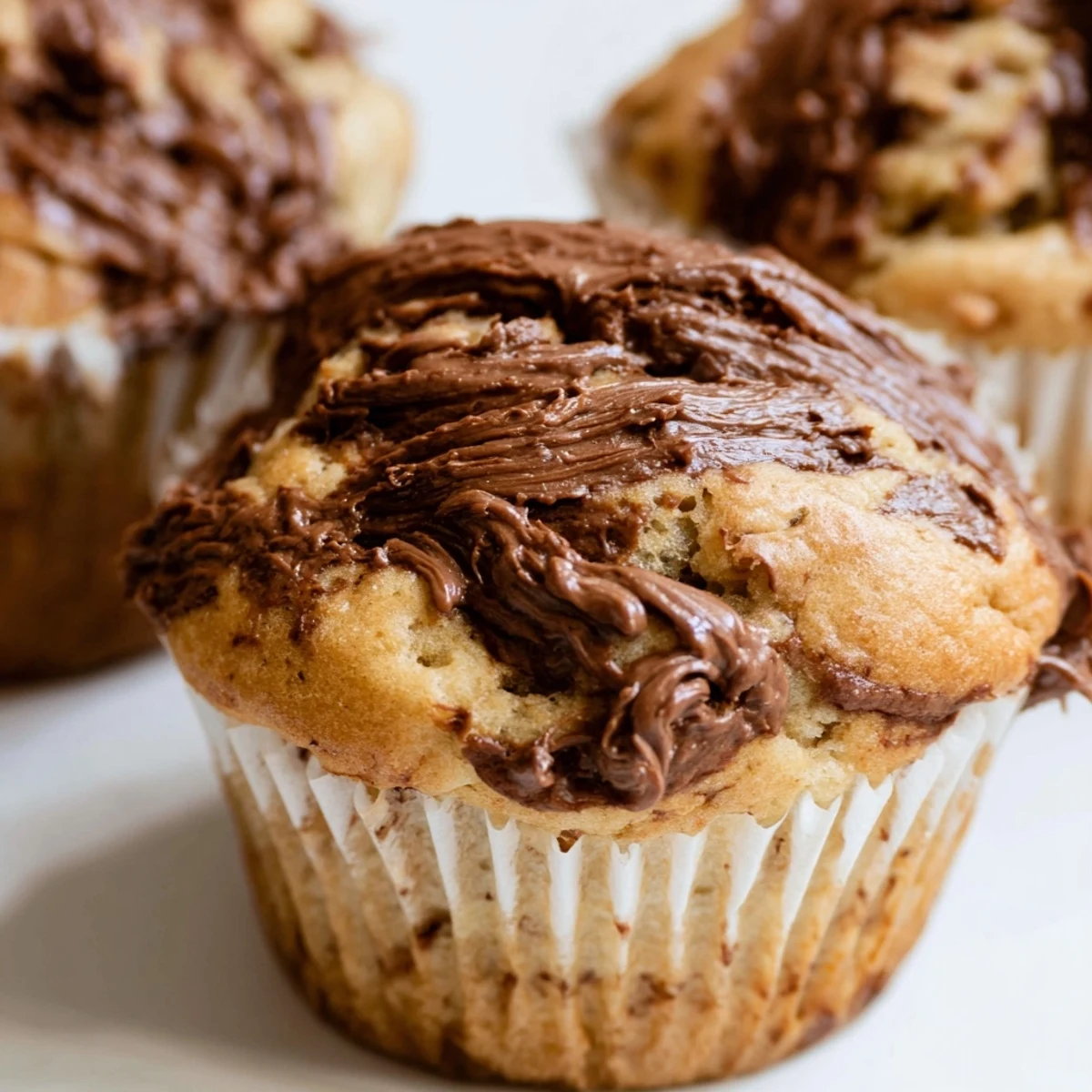 Freshly baked moist banana muffins with ribbons of creamy Nutella displayed on a wire cooling rack