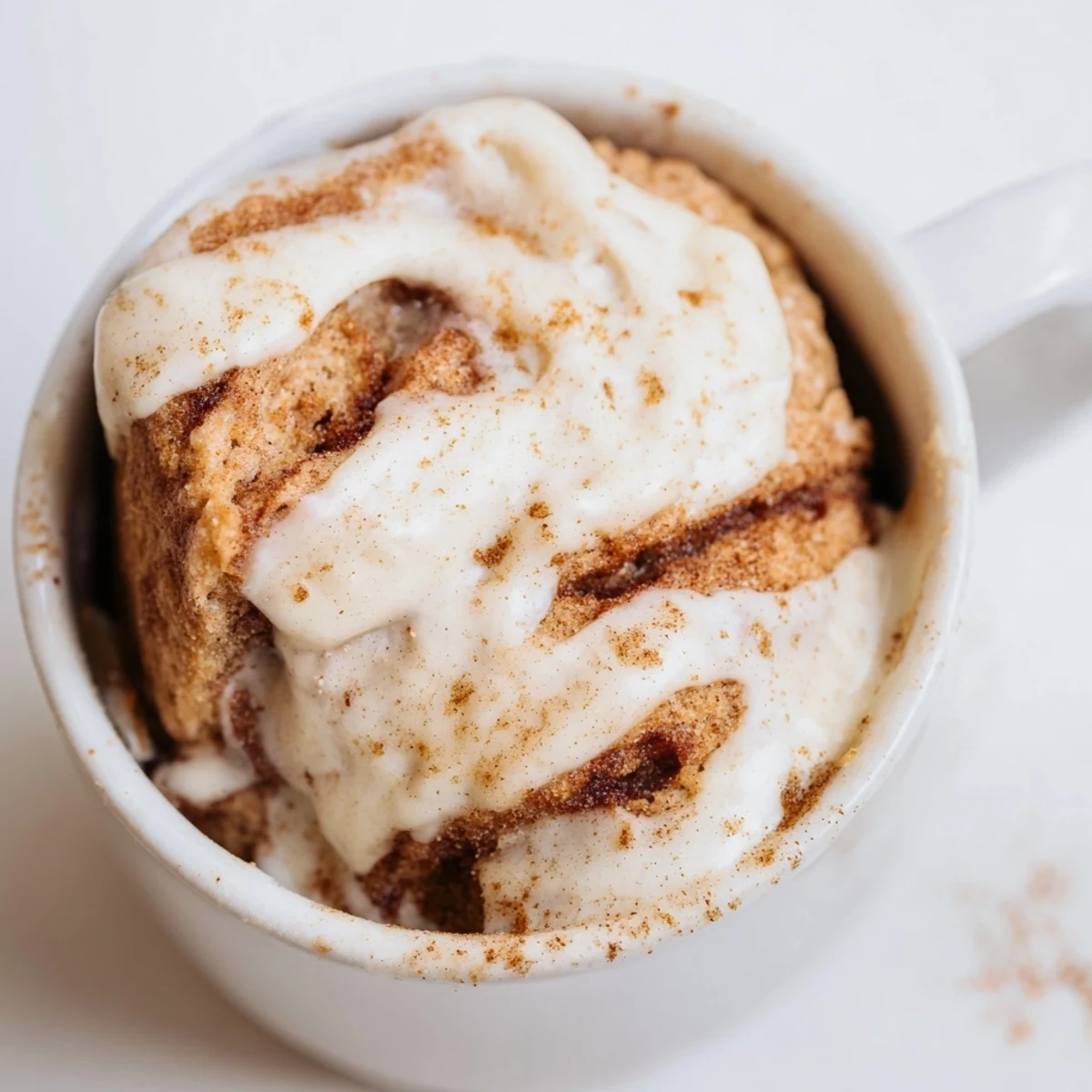 Warm high protein cottage cheese cinnamon roll mug cake drizzled with sweet cream cheese icing