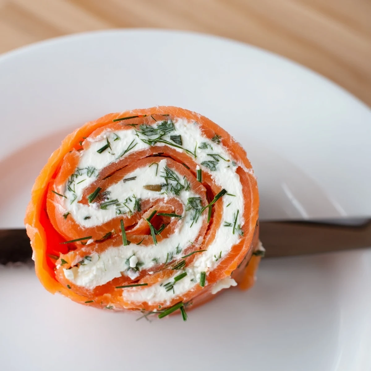 Appetizer spread featuring spiral smoked salmon roll ups with vibrant green herbs and smooth cream cheese filling