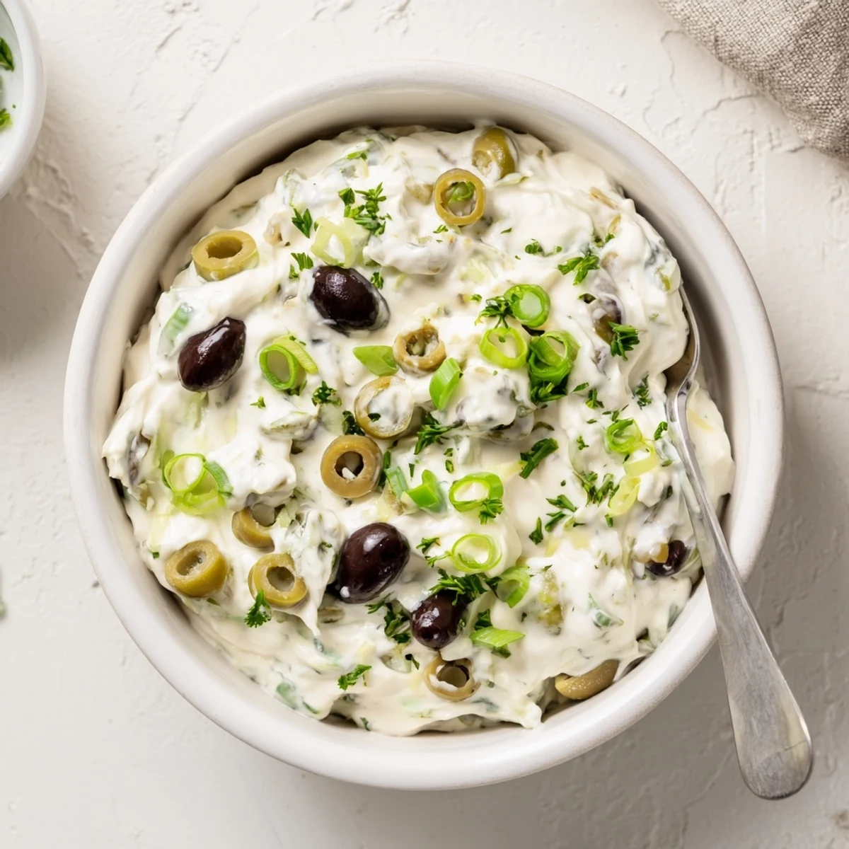 White cream cheese mixed with briny black and green olives garnished with fresh parsley