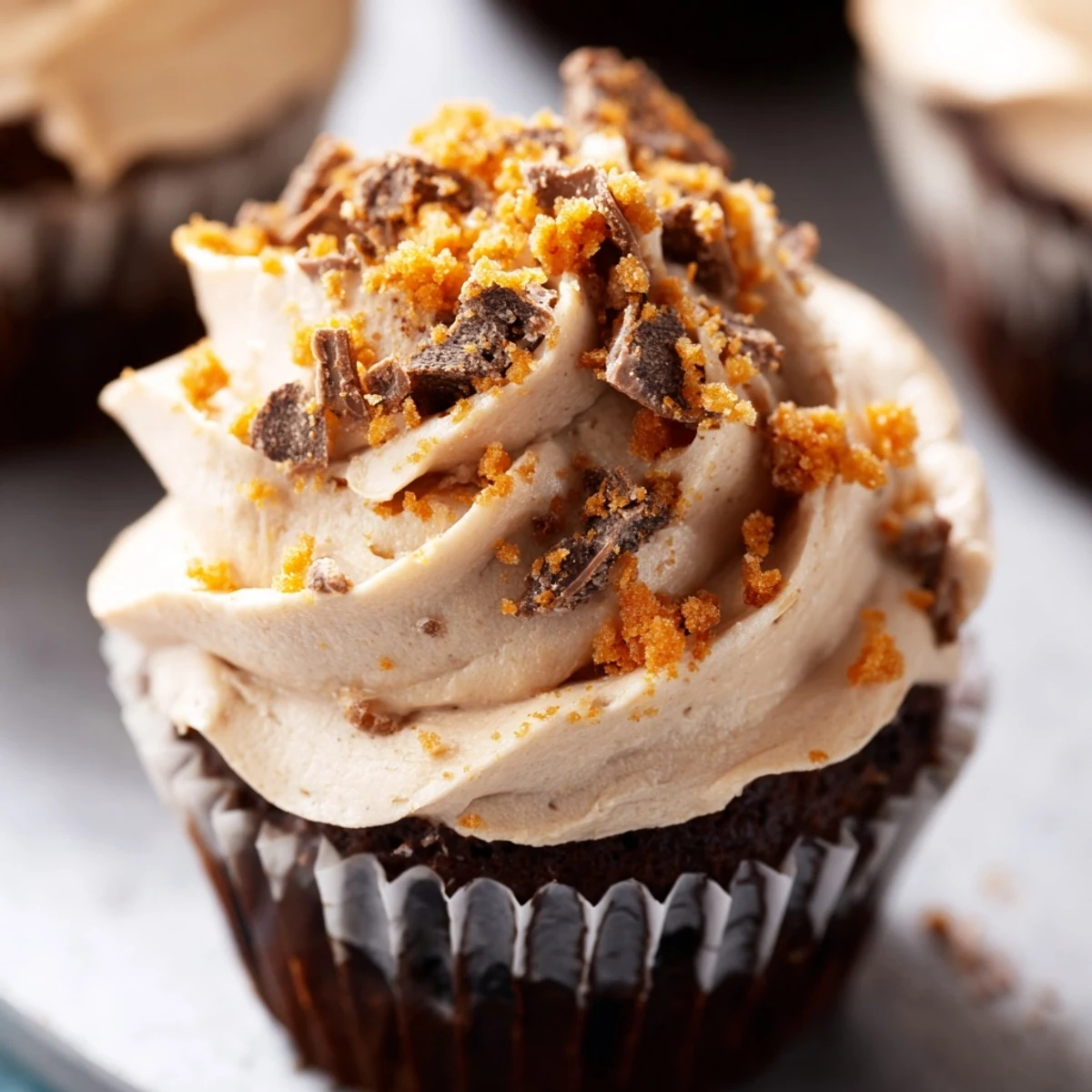 Stack of homemade Butterfinger cupcakes with crunchy candy topping and smooth peanut butter center