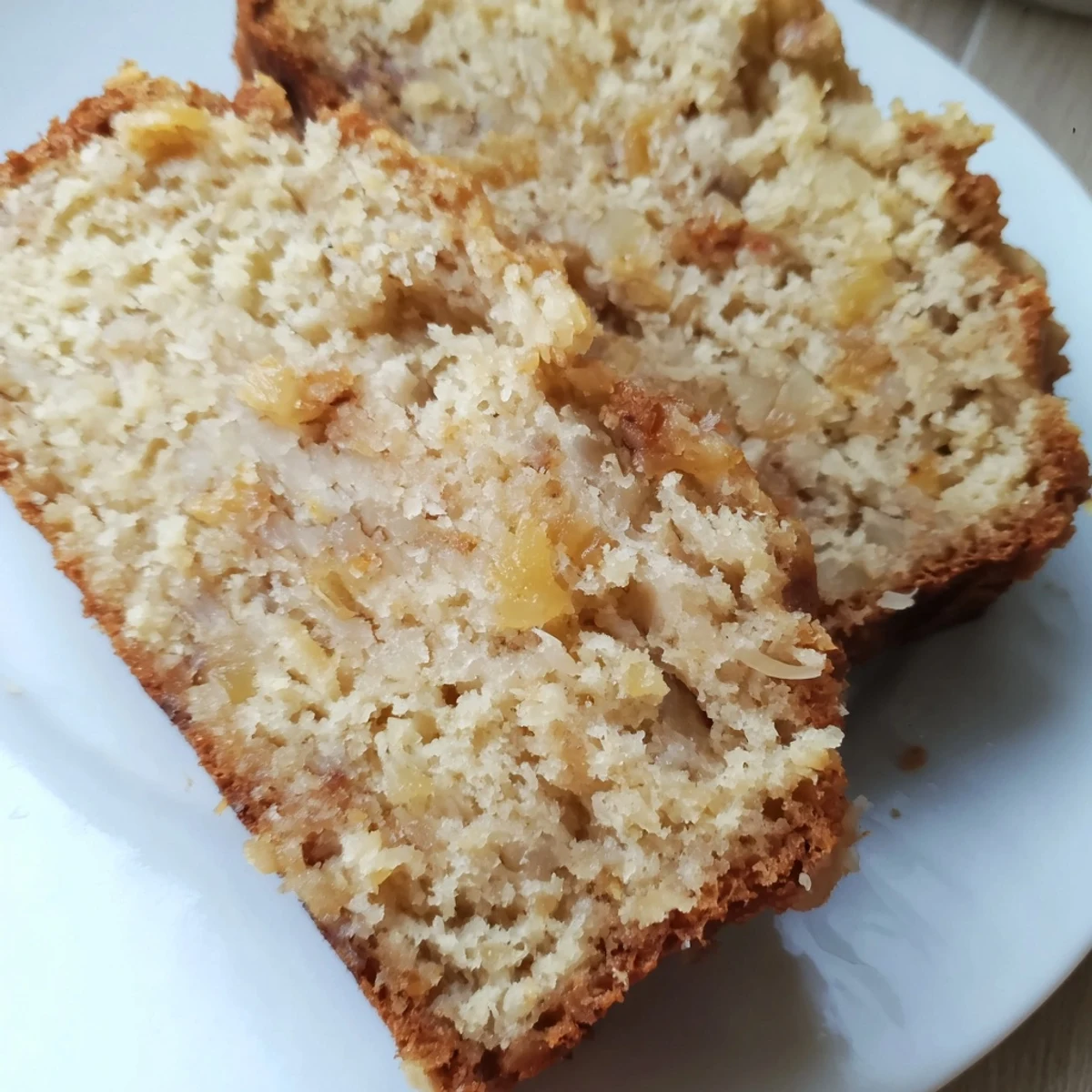 Warm slice of pineapple coconut bread served on a plate, topped with melted butter and honey