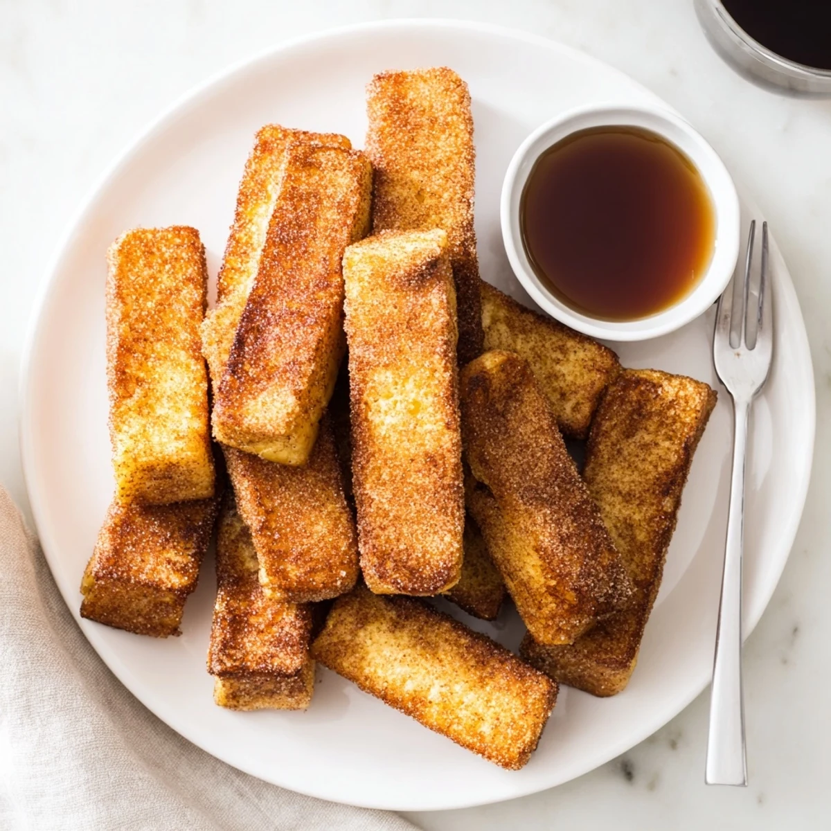 Hand holding warm cinnamon French toast sticks coated in sugar, ready for breakfast dipping