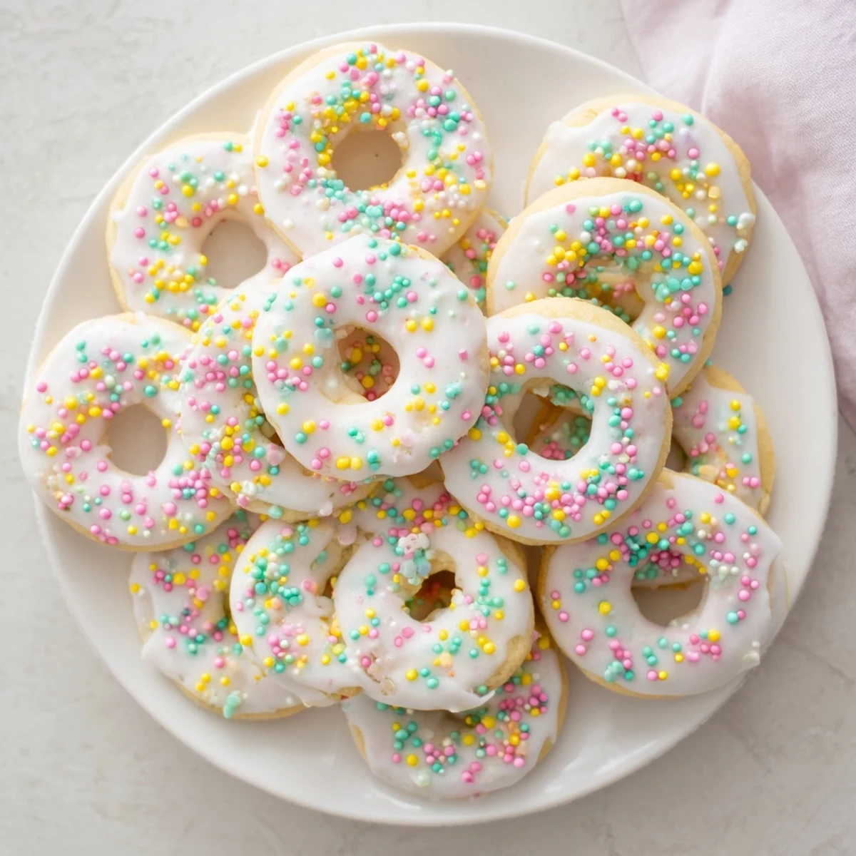 Ring-shaped Italian Easter cookies with lemon glaze and festive nonpareils arranged on a parchment-lined baking sheet.