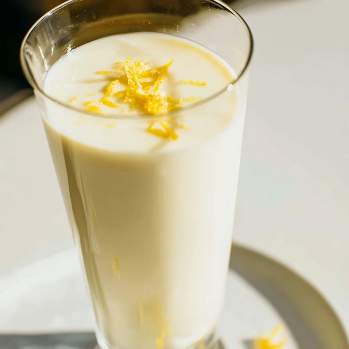 Silky smooth lemon posset set in clear glasses topped with fresh lemon zest
