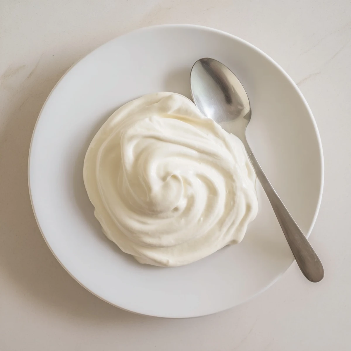 Creamy white Greek yogurt spoon resting in glass bowl after straining to thick perfection