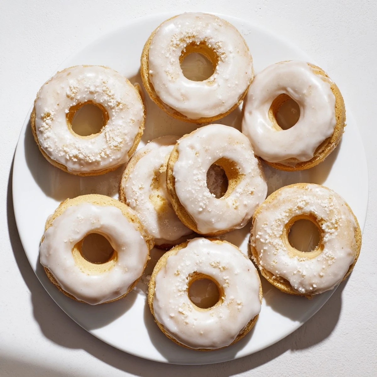 Golden baked Greek yogurt cake donuts topped with sweet vanilla glaze and colorful sprinkles on a white plate