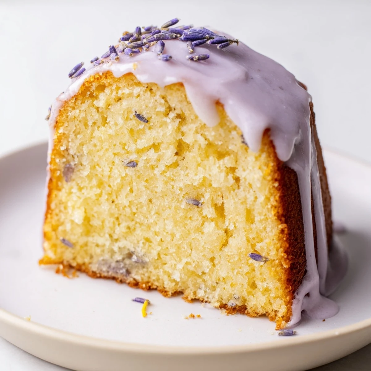 Soft lavender cake topped with sweet citrus icing on a white plate