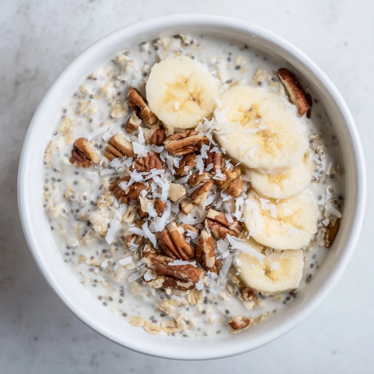 Creamy Coconut Cream Pie Overnight Oats topped with toasted coconut flakes and pecans in a mason jar