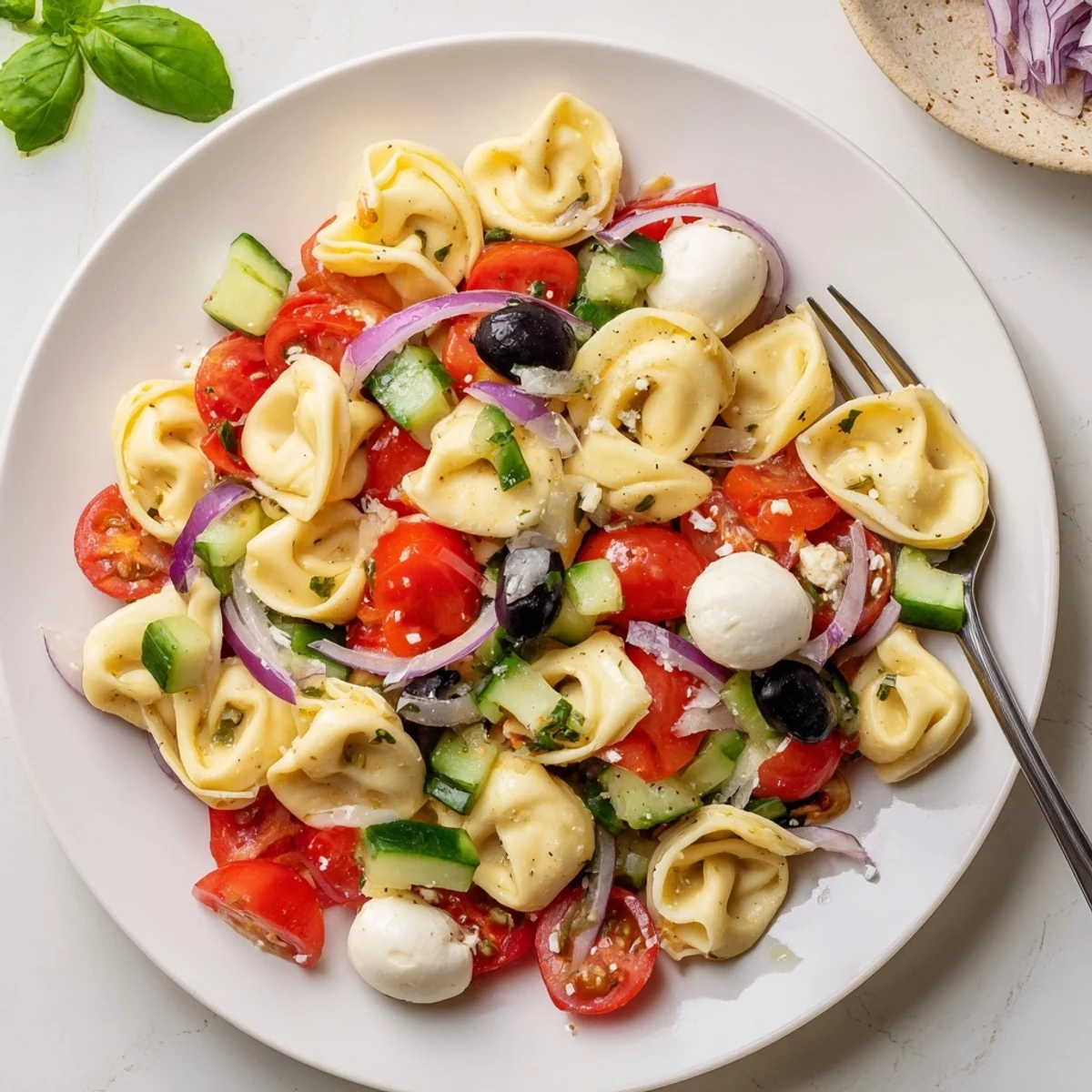 Tortellini salad featuring tender pasta, crisp vegetables, and herbs in zesty vinaigrette