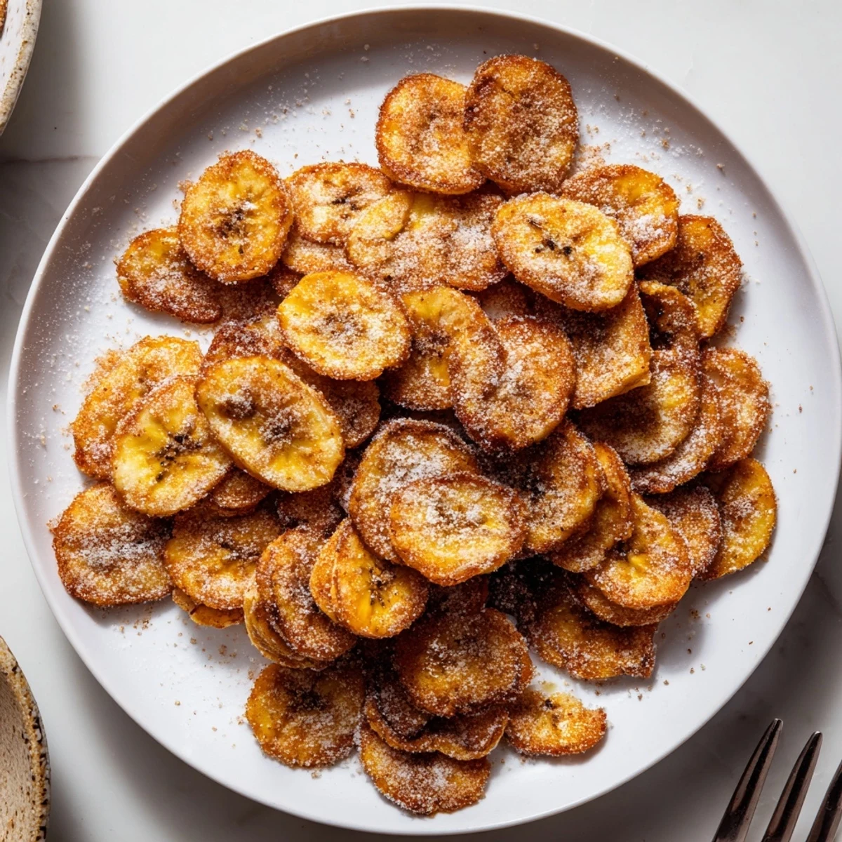 Hands reaching for Crispy Cinnamon Sugar Air Fryer Banana Chips beside coffee