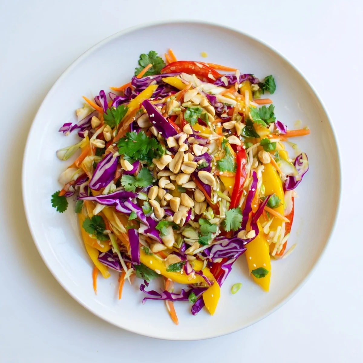 Fresh mango slaw topped with sesame seeds displaying red cabbage carrots and cilantro