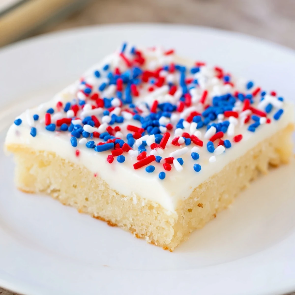 Soft 4th of July sugar cookie bars topped with creamy vanilla frosting and red white blue sprinkles