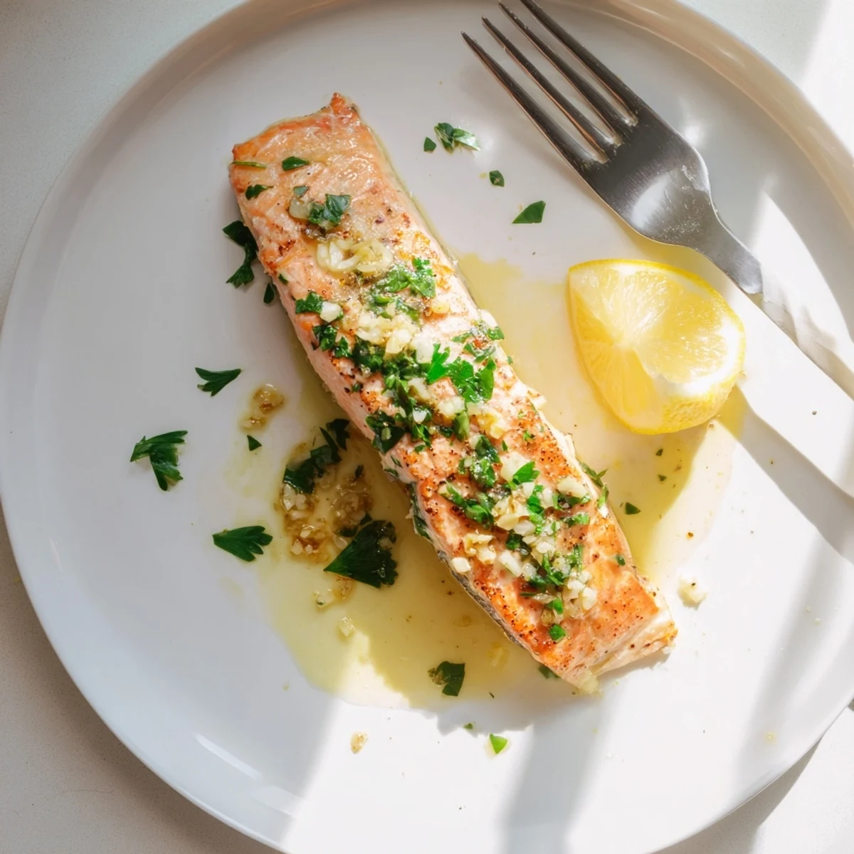Restaurant-worthy pan seared salmon plated with fresh parsley and bright lemon wedges