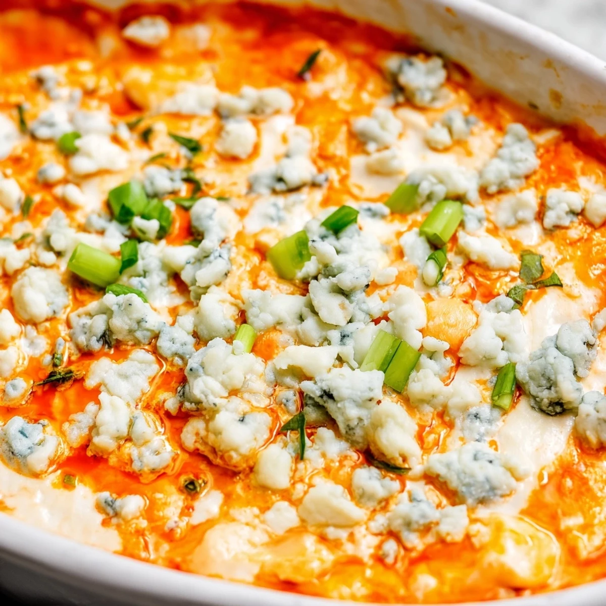 Creamy cheesy white bean buffalo dip in a baking dish, garnished with parsley and served warm for parties