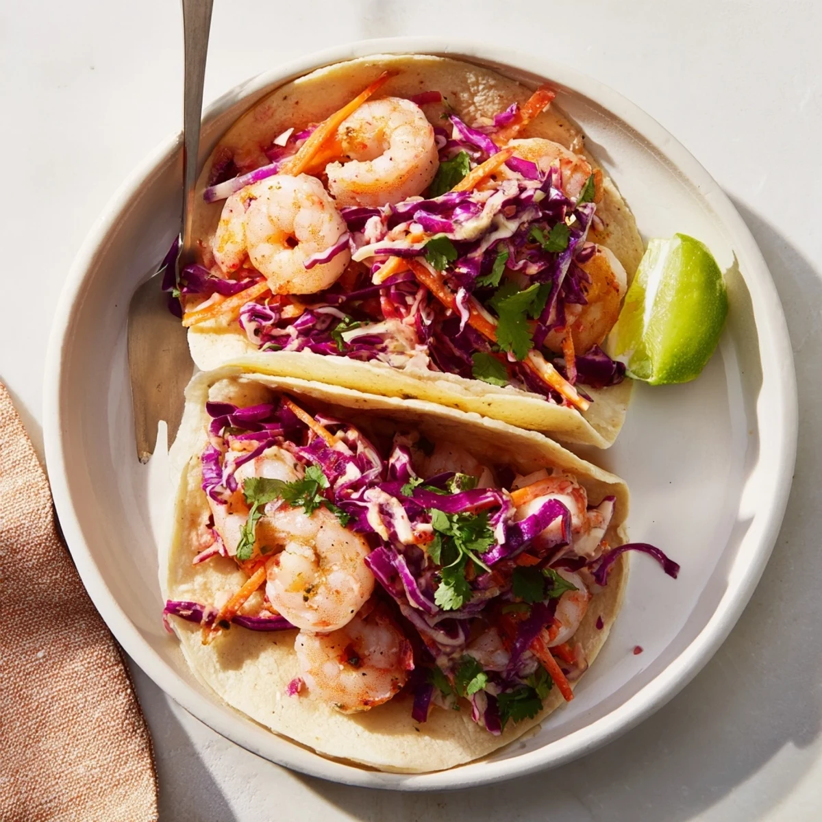 Spicy shrimp tacos featuring juicy pink seafood atop crisp red and green cabbage slaw in soft corn tortillas