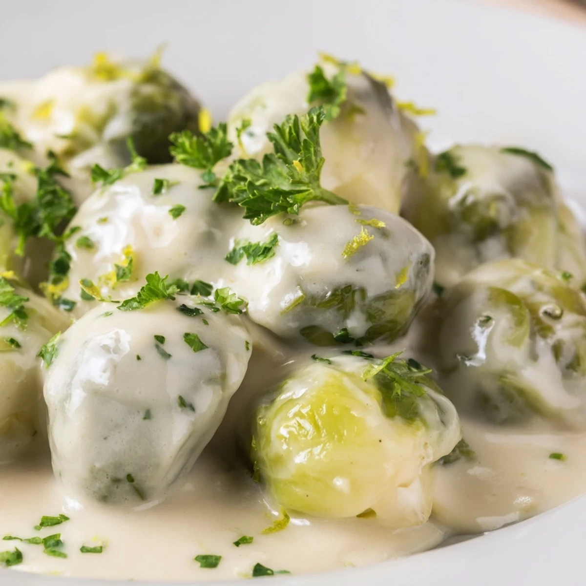 Sautéed Brussels sprouts halved and swimming in rich garlic herb cheese sauce with black pepper