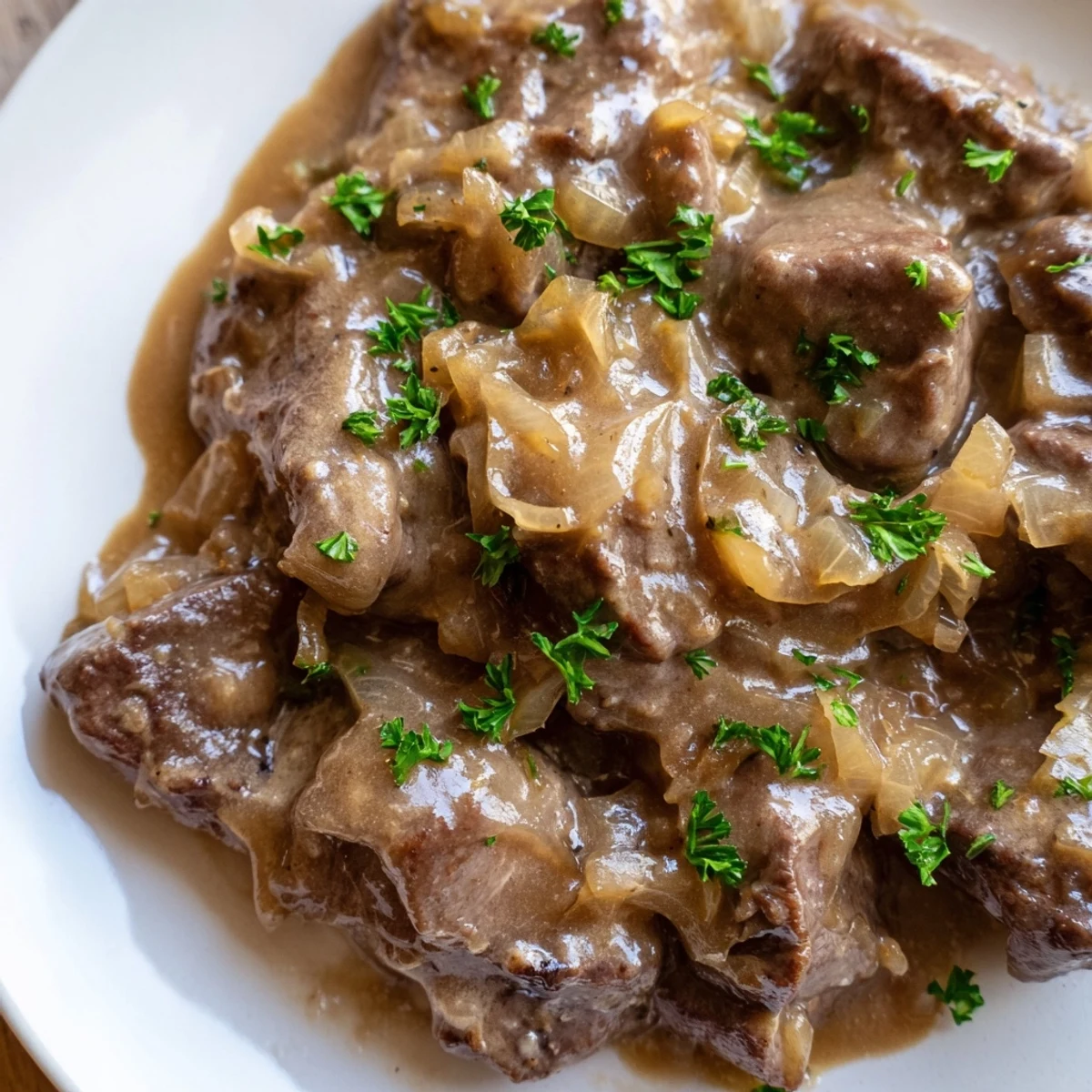 Tender cube steak pieces simmered in thick savory gravy topped with caramelized onions and fresh parsley