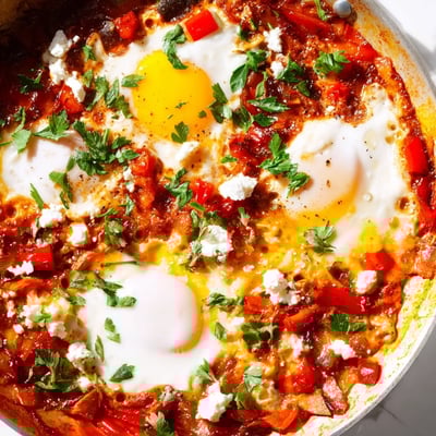 Four poached eggs simmer in vibrant red pepper and tomato sauce for this Quick Shakshuka Eggs recipe.