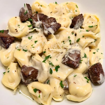 Sizzling steak bites nestled among plump cheese tortellini drenched in silky garlic cream